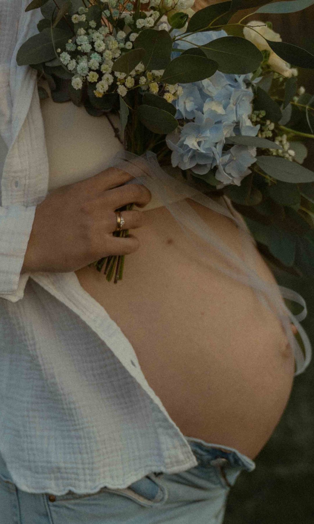 Eine schwangeren Frau mit Blumenstrauß in der Hand bei einem Babybauchshooting